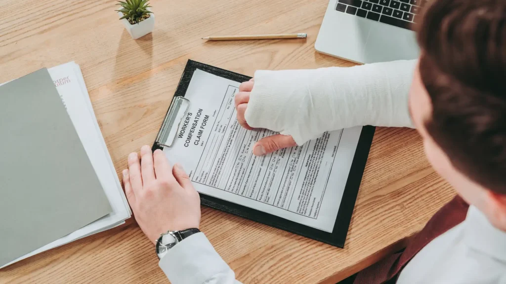 Person with a cast signing a document on a clipboard.